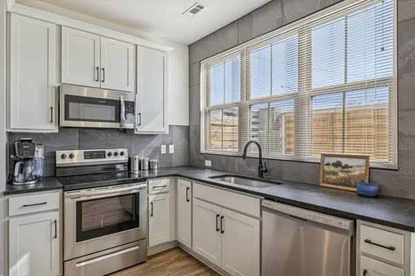 a kitchen with stainless steel appliances granite countertop a stove a sink and white cabinets
