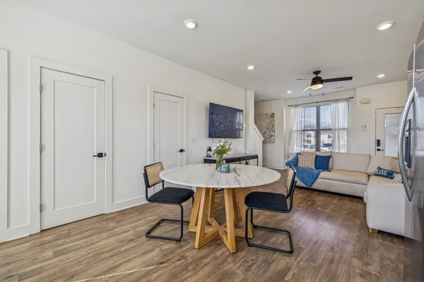 a living room with couches and kitchen view with wooden floor