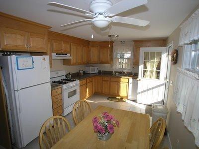 5 Wood Road Dennis Port, MA 02639 - Photo 4 of 7 a kitchen with stainless steel appliances granite countertop a refrigerator a stove a sink dishwasher and white cabinets with wooden floor