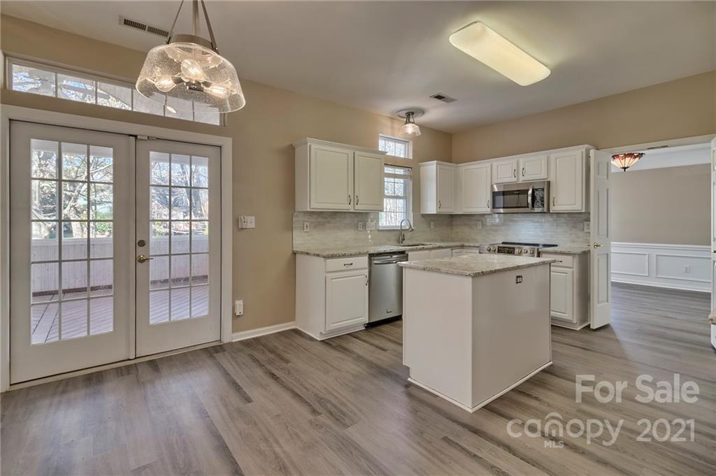 4821 Brownes Ferry Road Charlotte, NC 28269 - Photo 4 of 37 a kitchen with stainless steel appliances granite countertop a stove a sink dishwasher a refrigerator and a dining table with wooden floor