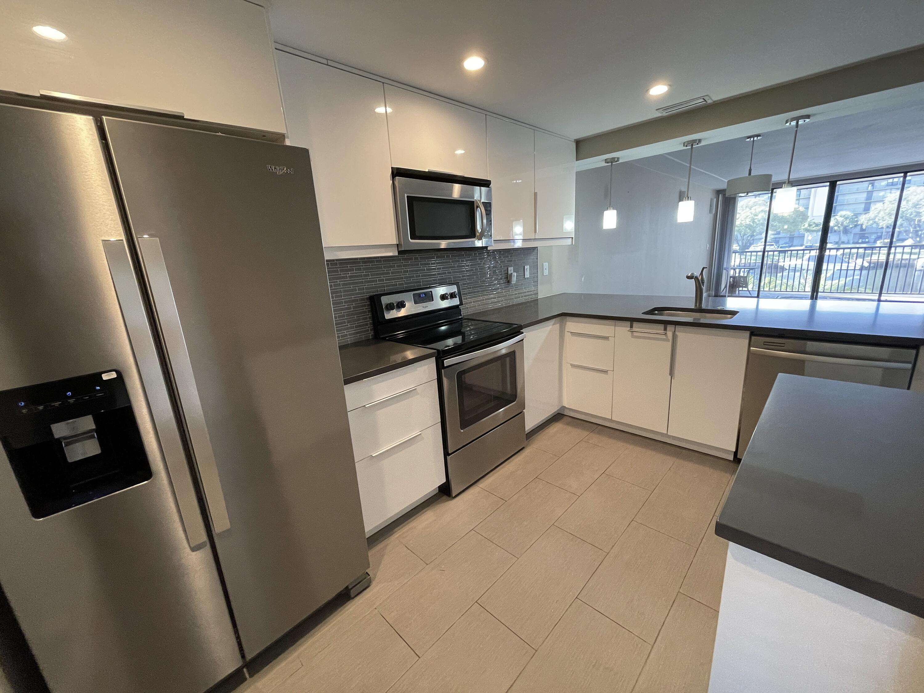 3 Royal Palm Way, Unit 2050 Boca Raton, FL 33432 - Photo 6 of 25 a kitchen with granite countertop a refrigerator a sink a stove a microwave a counter top and cabinets