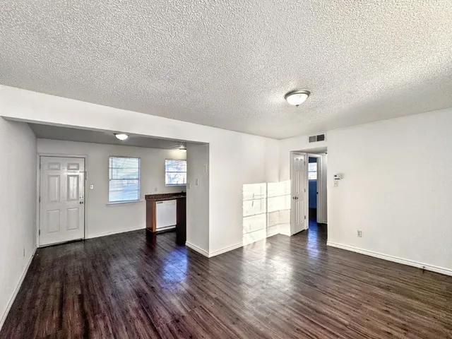 a view of an empty room with window and wooden floor