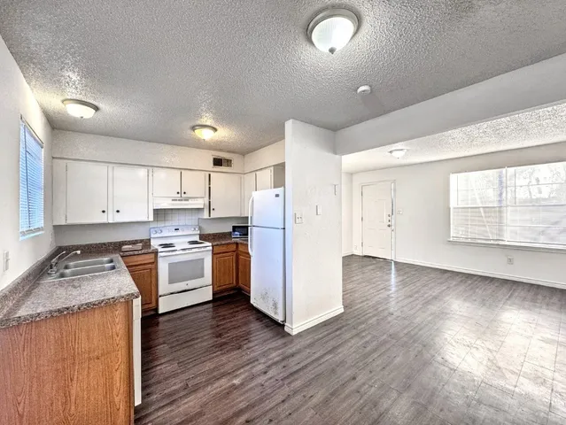 a kitchen with a refrigerator a stove top oven and wooden floors