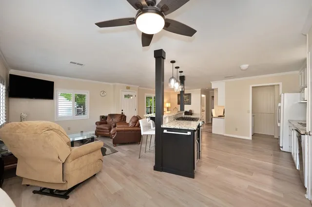 a living room with stainless steel appliances kitchen island granite countertop furniture and a chandelier