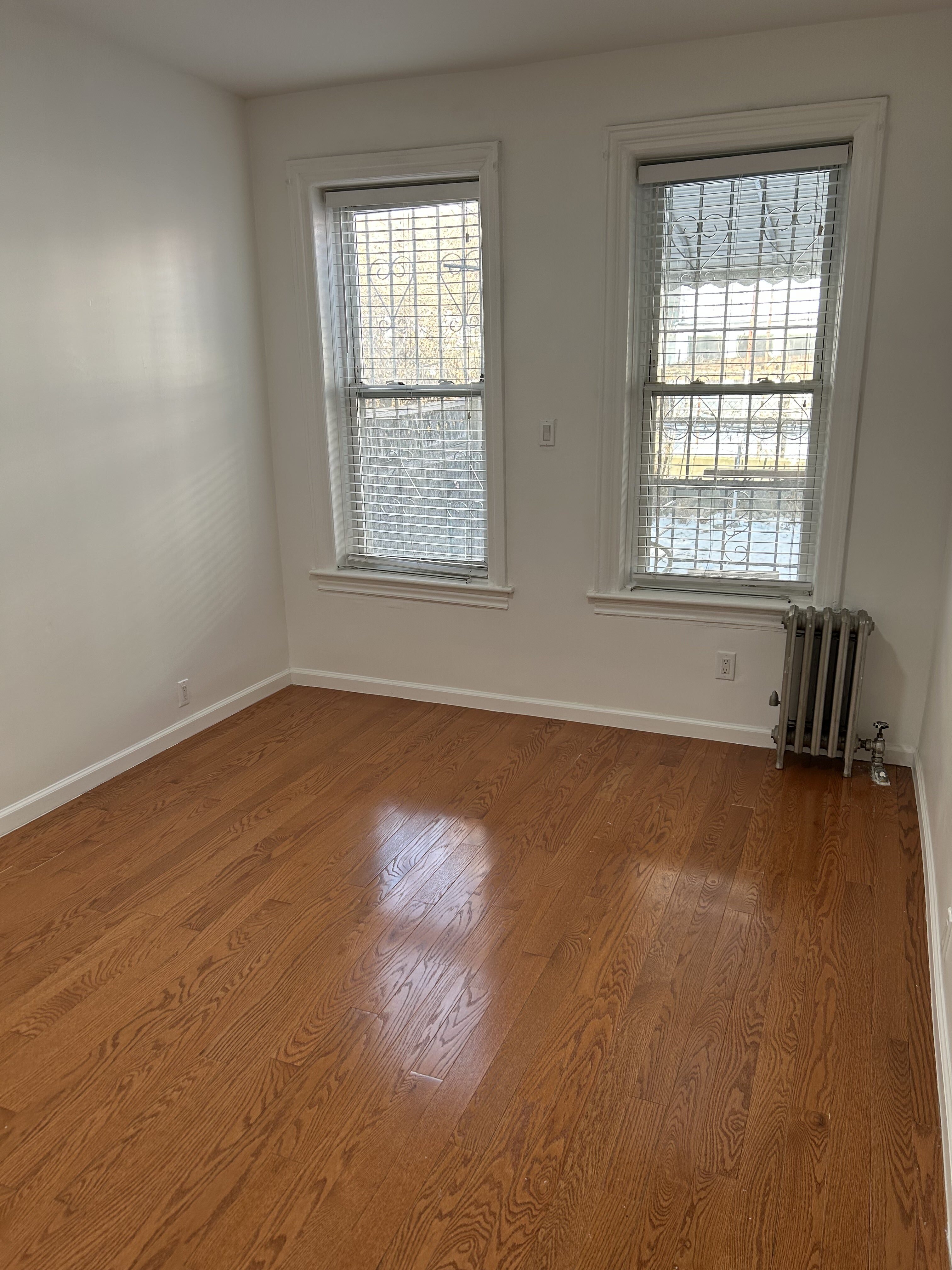 839 53rd Street, Unit 1 Brooklyn, NY 11220 - Photo 5 of 10 an empty room with wooden floor and windows