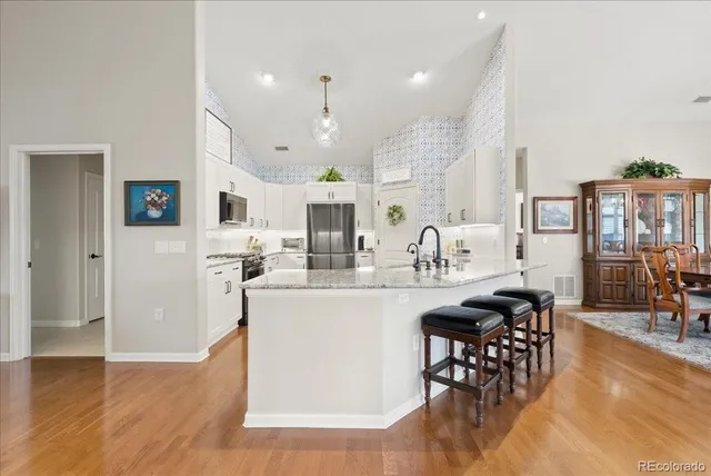 a living room with stainless steel appliances kitchen island granite countertop furniture and a wooden floor