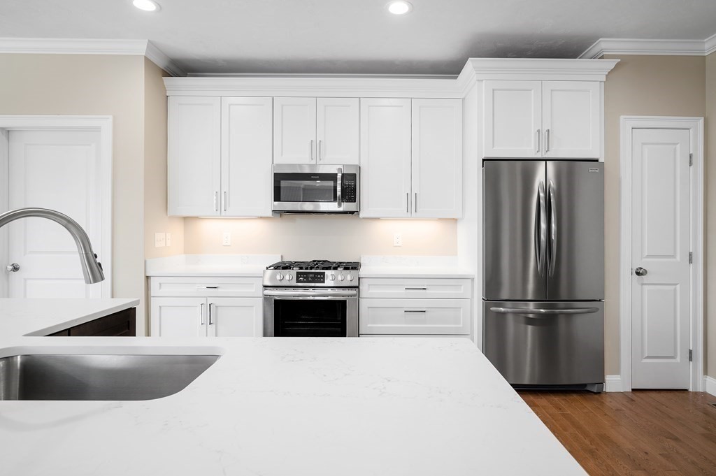 159 Rolling Rdg Drive, Unit 85 Northbridge, MA 01588 - Photo 8 of 25 a kitchen with refrigerator a stove top oven and white cabinets