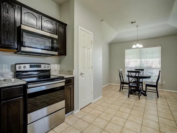 a kitchen with stainless steel appliances granite countertop a stove top oven a sink dishwasher a dining table and chairs with wooden floor