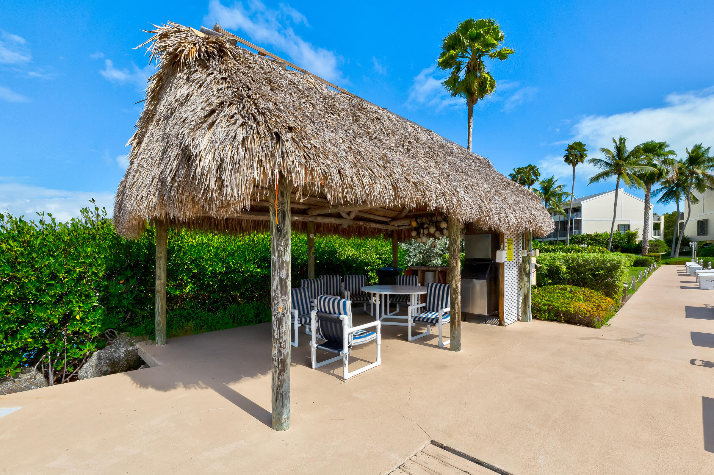 94220 Overseas Highway, Unit 5E Tavernier, FL 33037 - Photo 52 of 77 a view of a patio with a table and chairs under an umbrella with a garden