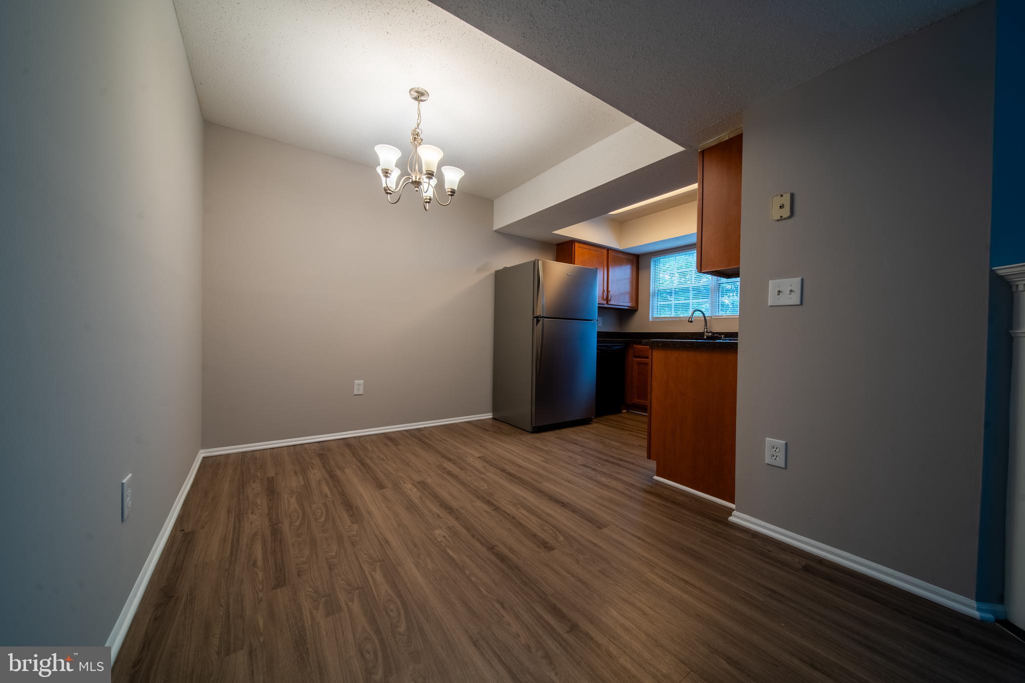 120 Fort Evans Road Southeast, Unit E Leesburg, VA 20175 - Photo 8 of 29 an empty room with wooden floor and chandelier