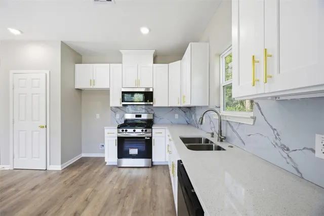 a kitchen with stainless steel appliances a stove a sink a refrigerator a window