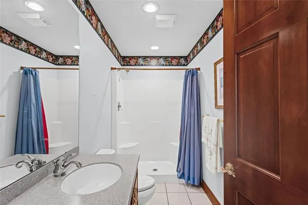 a bathroom with a sink a toilet a mirror and shower