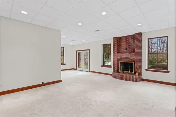 an empty room with windows and fireplace