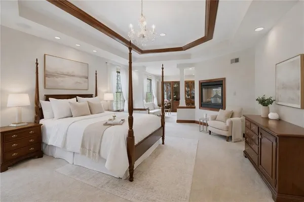 a spacious bedroom with a bed couch chandelier and a large window
