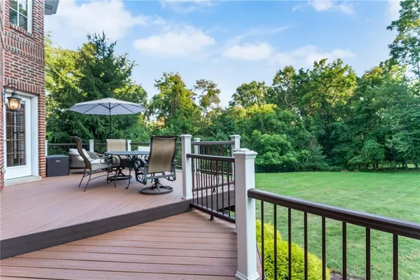 a view of a chair and tables under an umbrella on the wooden deck