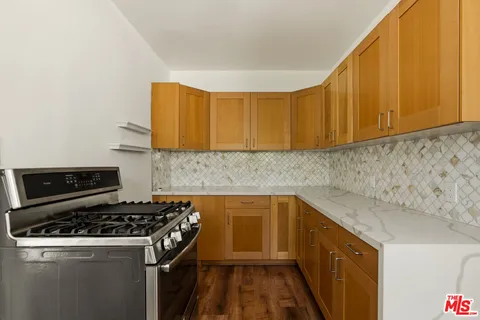 a kitchen with a sink a stove cabinets and wooden floor