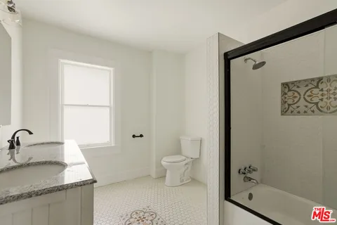 a bathroom with a granite countertop sink a toilet and shower