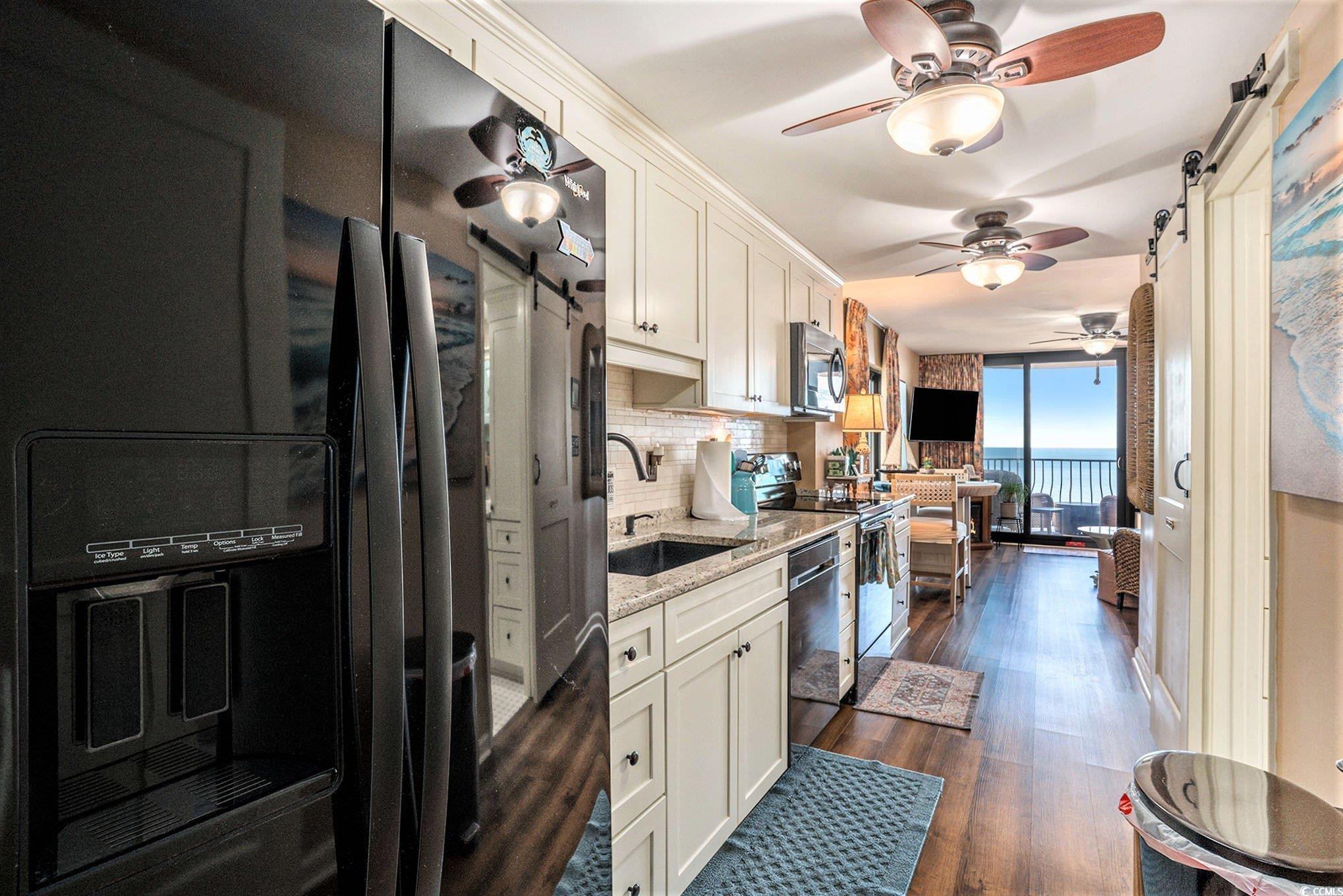 2406 North Ocean Boulevard, Unit 1203 Myrtle Beach, SC 29577 - Photo 8 of 24 Kitchen with a barn door, appliances with stainless steel finishes, decorative backsplash, and light stone counters