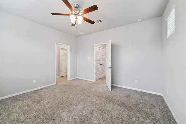 an empty room with closet and a ceiling fan
