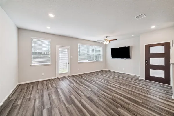 a view of an empty room with wooden floor and a window