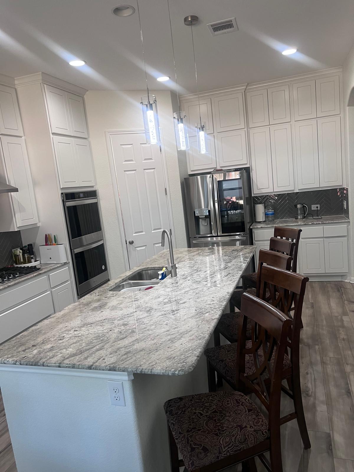 1837 Halflinger Lane Leander, TX 78641 - Photo 8 of 39 Kitchen featuring dark wood-style floors, decorative backsplash, a kitchen bar, light stone countertops, and an island with sink