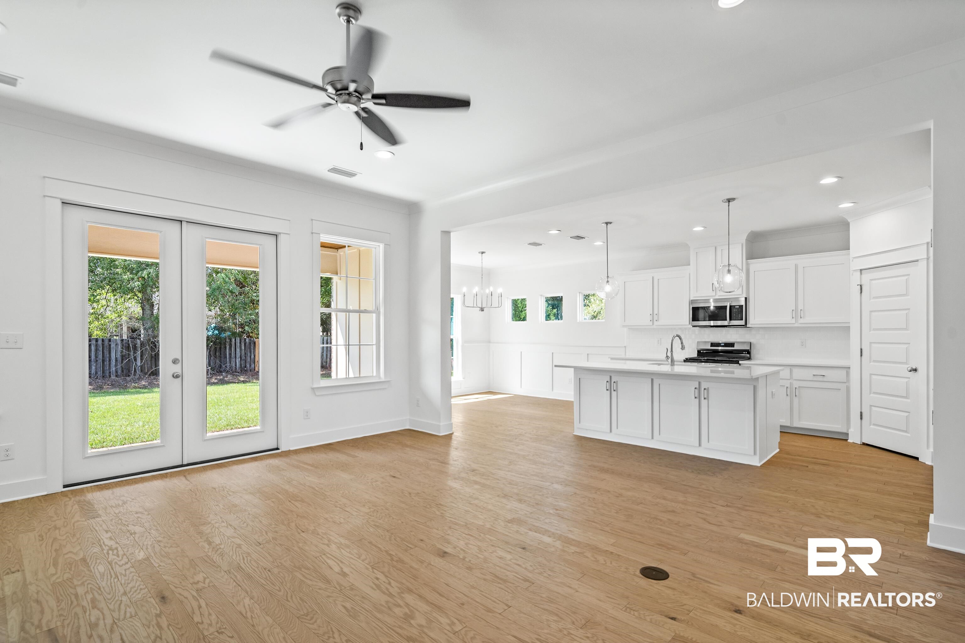 25927 Capra Court Daphne, AL 36526 - Photo 8 of 37 Kitchen featuring hanging light fixtures, white cabinetry, ceiling fan with notable chandelier, stainless steel appliances, and a kitchen island with sink