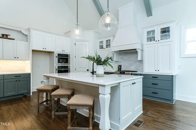 a kitchen with white cabinets and wooden floors