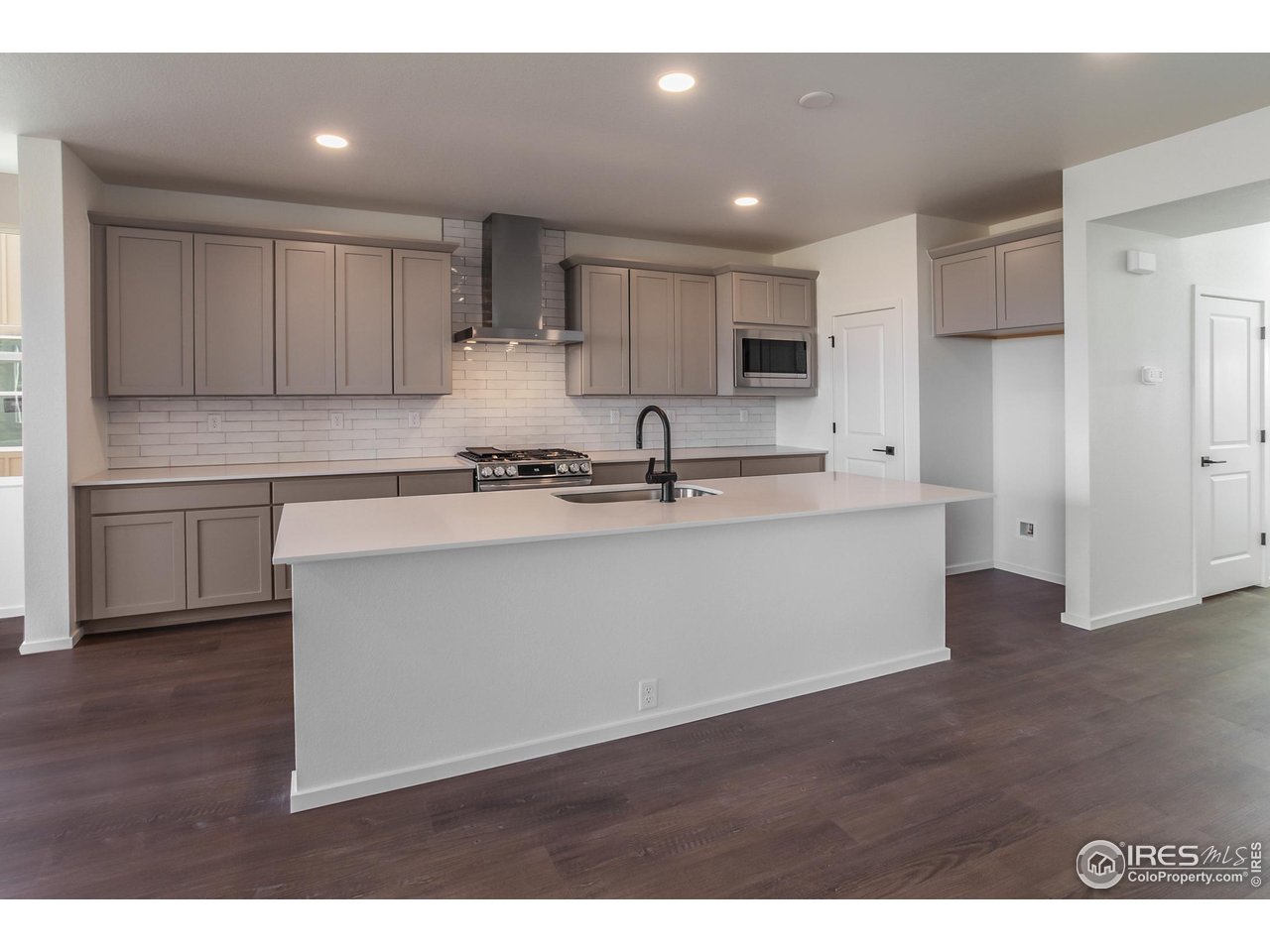 768 Chatter Road Windsor, CO 80550 - Photo 7 of 37 a kitchen with stainless steel appliances granite countertop a sink dishwasher a refrigerator and white cabinets with wooden floor