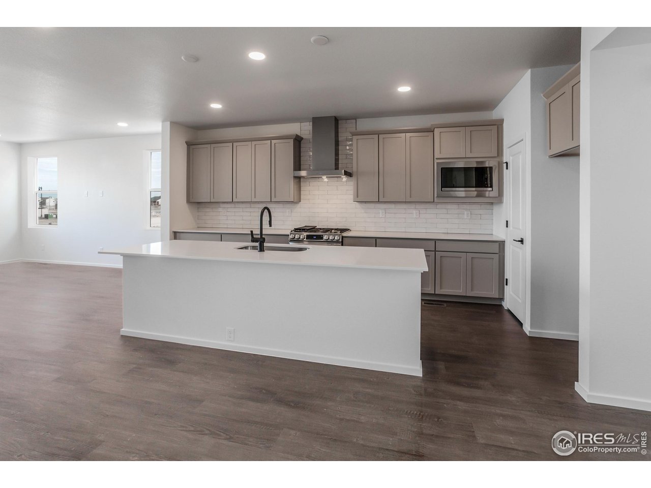 768 Chatter Road Windsor, CO 80550 - Photo 8 of 37 a kitchen with stainless steel appliances granite countertop a sink a stove a refrigerator with white cabinets and wooden floor
