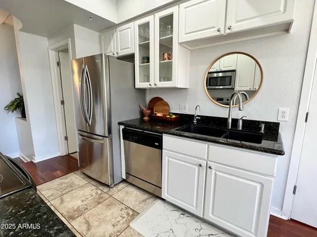 a kitchen with stainless steel appliances granite countertop a refrigerator a stove and a sink with wooden floor