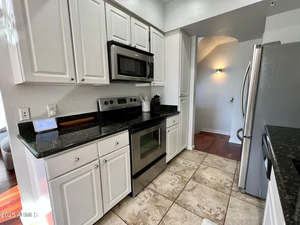 a kitchen with granite countertop white cabinets and stainless steel appliances
