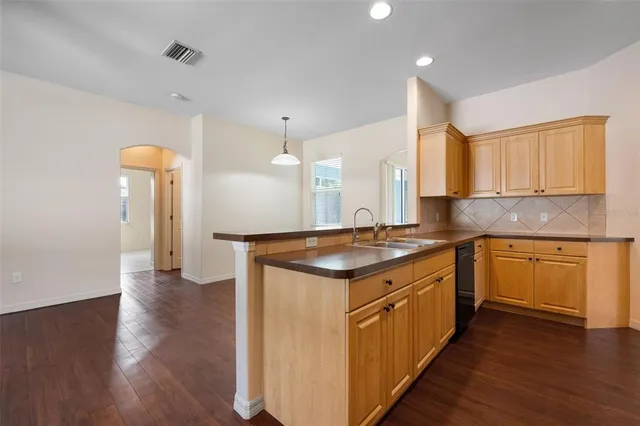 a kitchen with stainless steel appliances granite countertop a sink a stove and a wooden floors
