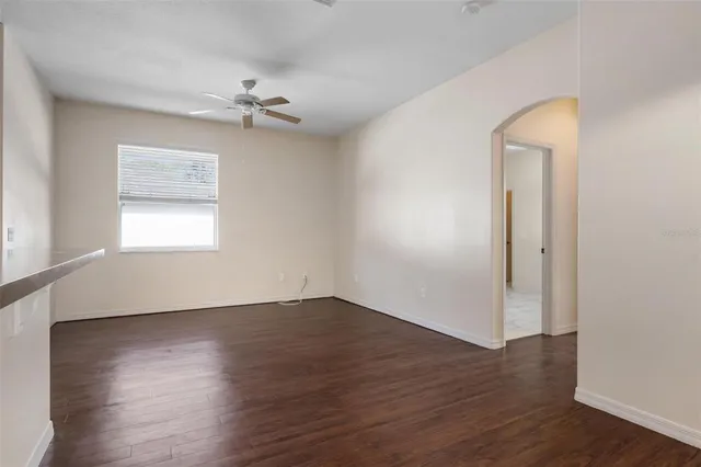 an empty room with wooden floor chandelier fan and windows