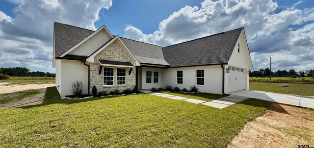 a view of a house with a big yard and large tree
