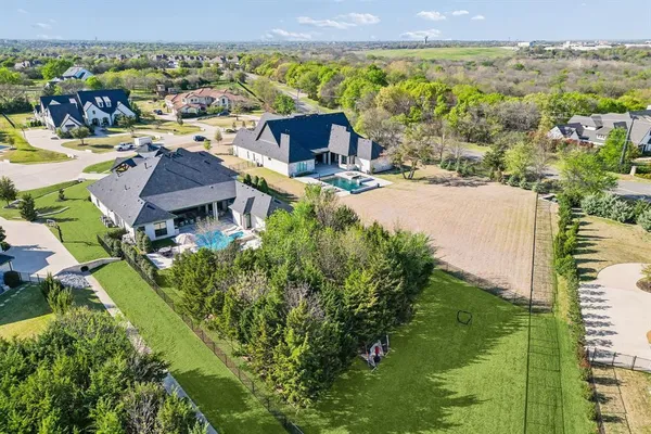 an aerial view of residential houses with outdoor space and trees