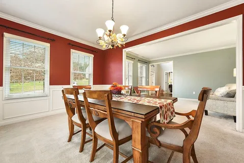 a view of a dining room with furniture a chandelier and a window