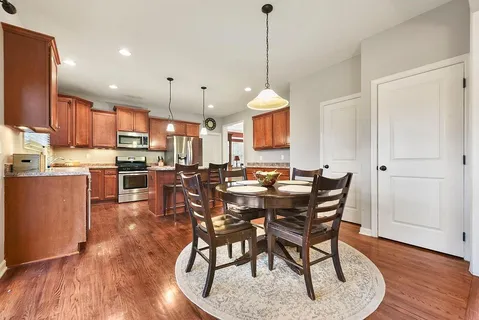 a view of a dining room and livingroom with furniture wooden floor a rug a rug a fireplace and a chandelier