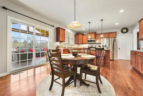 a dining room with stainless steel appliances granite countertop a stove a sink a dining table and chairs with wooden floor