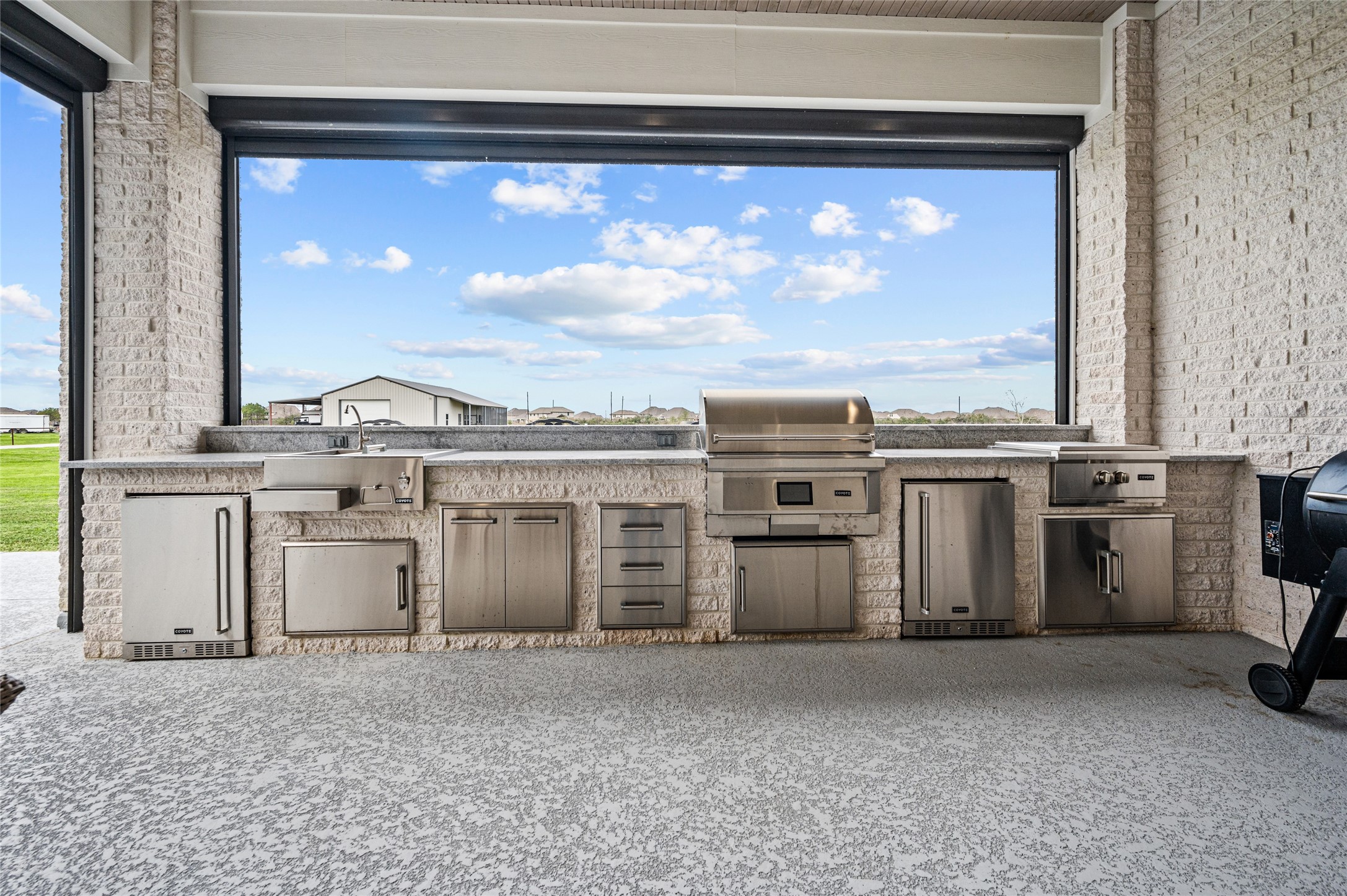 14923 Old Irish Farm Road Baytown, TX 77523 - Photo 36 of 50 Outdoor kitchen equipped with Motorized cooling shades with AC unit, Granite counters, gas grill/smoker and large burner, 2 refrigerators, built-in trashcans, drawers and under counter storage space