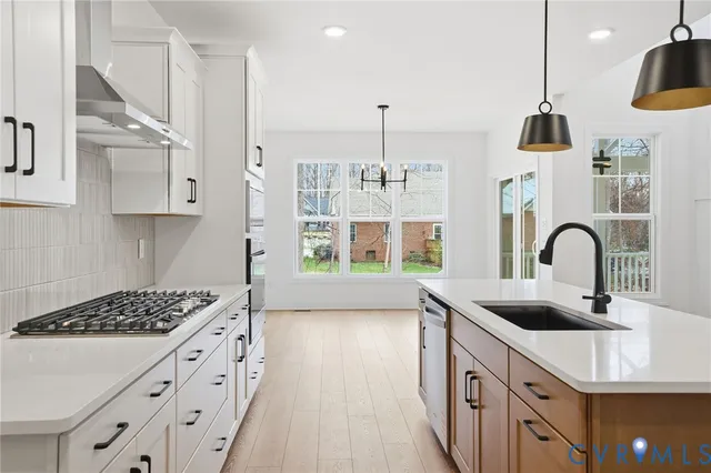 a kitchen with stainless steel appliances a sink stove and white cabinets with wooden floor