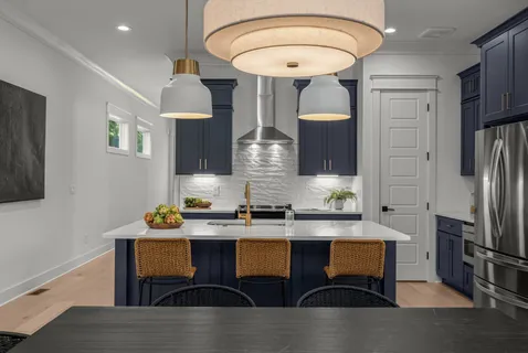 a kitchen with stainless steel appliances granite countertop a dining table chairs and a refrigerator