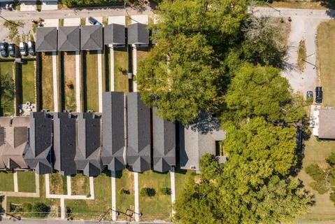 a view of a brick house with a small yard and large trees