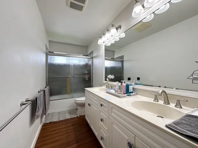 a bathroom with a double vanity sink mirror and shower