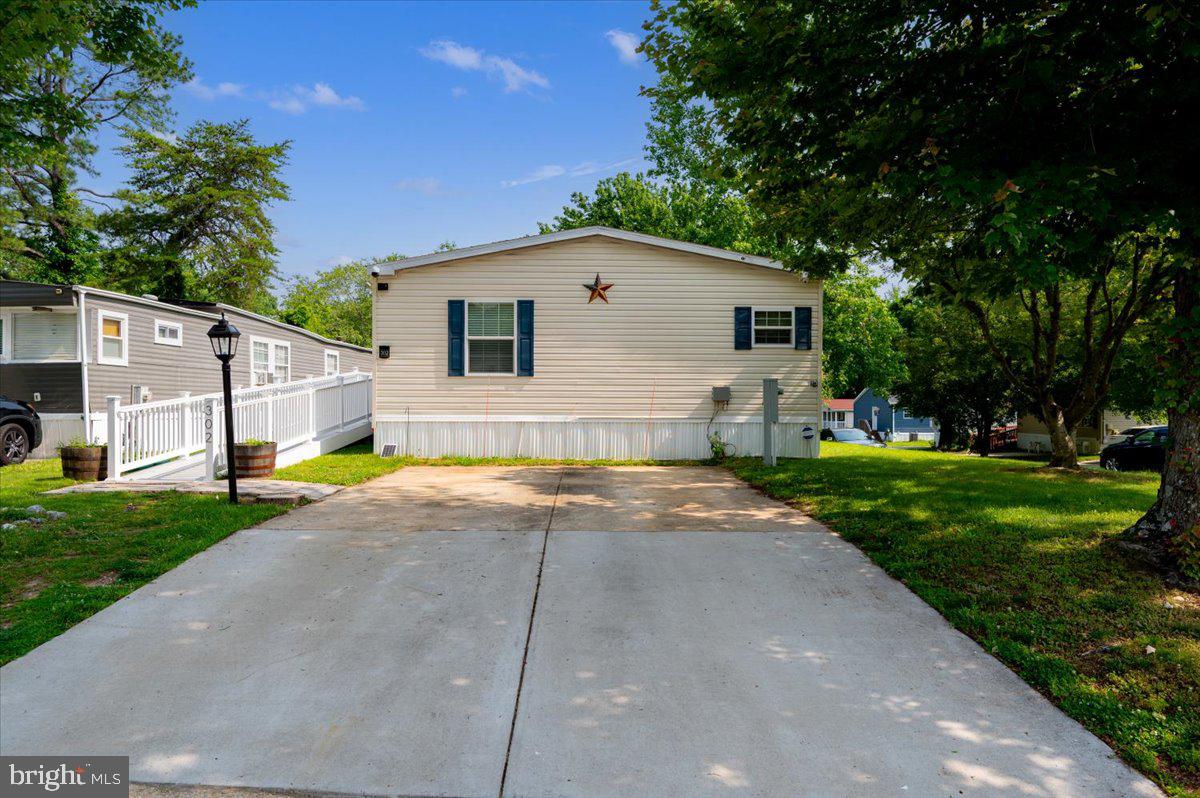 302 Berts Drive Lothian, MD 20711 - Photo 3 of 38 a view of a white house with a yard plants and large tree