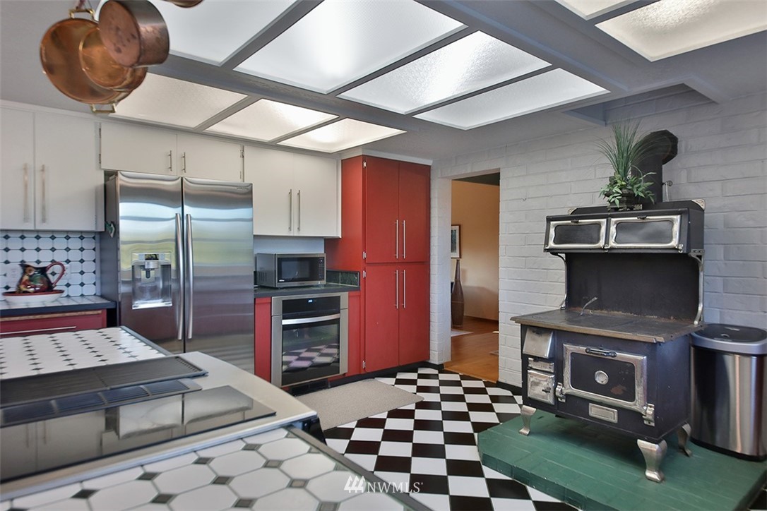 5749 Double Bluff Road Freeland, WA 98249 - Photo 17 of 40 a kitchen with stainless steel appliances kitchen island granite countertop a stove refrigerator and cabinets