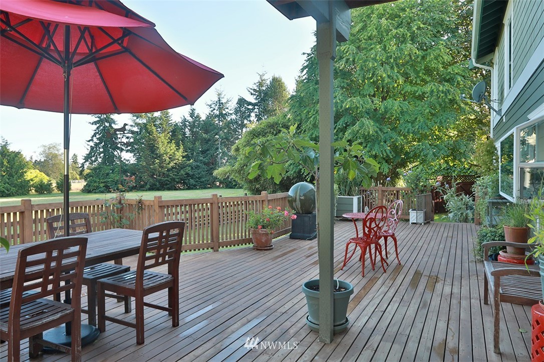 5749 Double Bluff Road Freeland, WA 98249 - Photo 8 of 40 a view of a roof deck with table and chairs under an umbrella with wooden floor