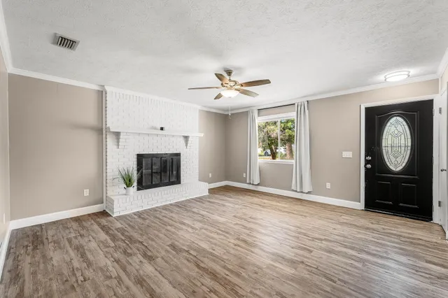 an empty room with wooden floor and a fireplace