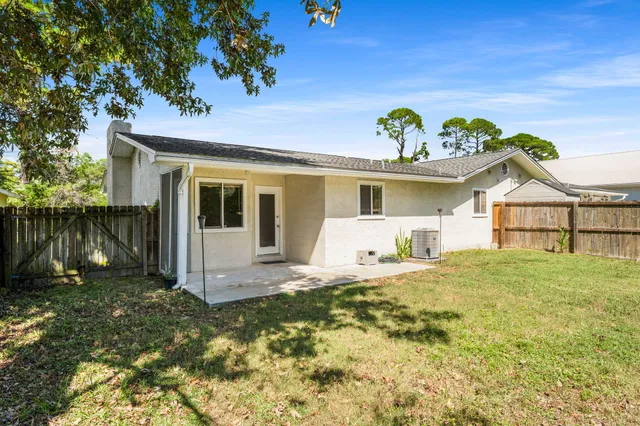 a backyard of a house with table and chairs and potted plants
