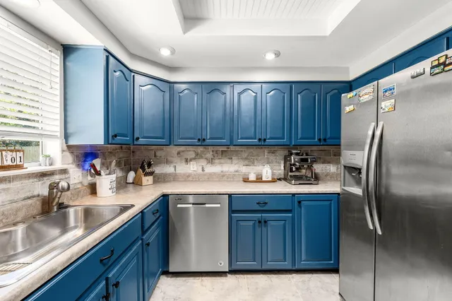 a kitchen with stainless steel appliances granite countertop a refrigerator a sink and wooden cabinets