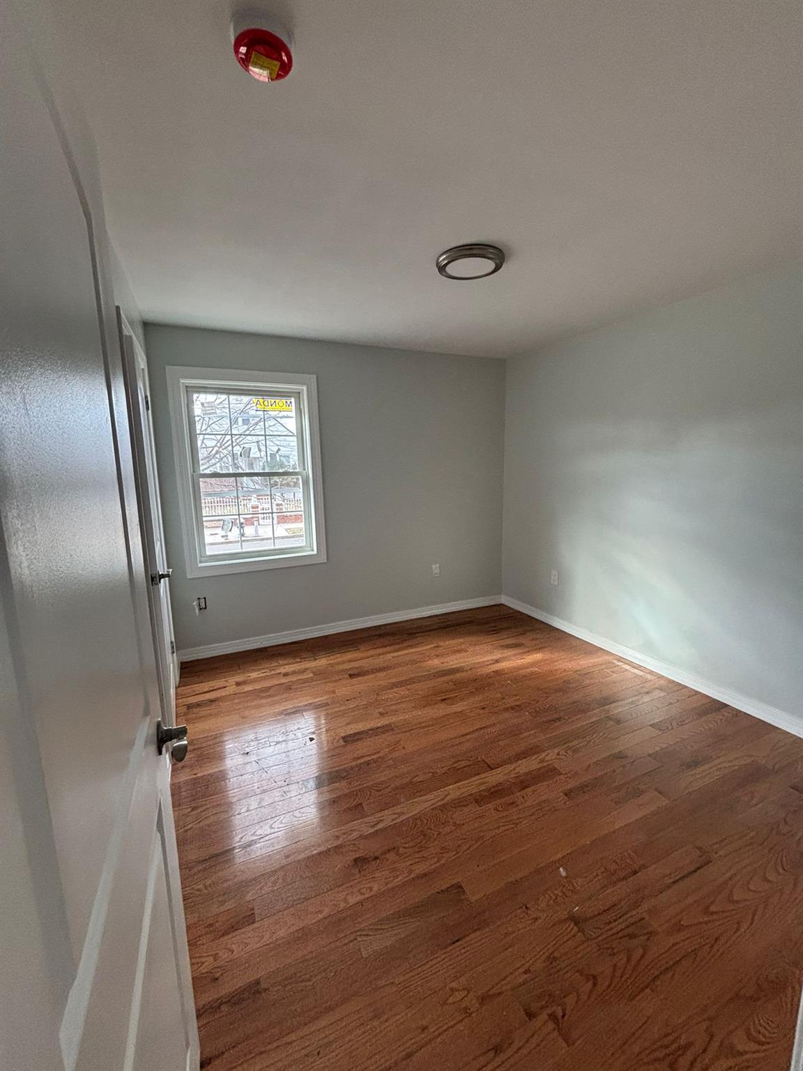 175-04 145th Drive Queens, NY 11434 - Photo 8 of 10 an empty room with wooden floor and windows